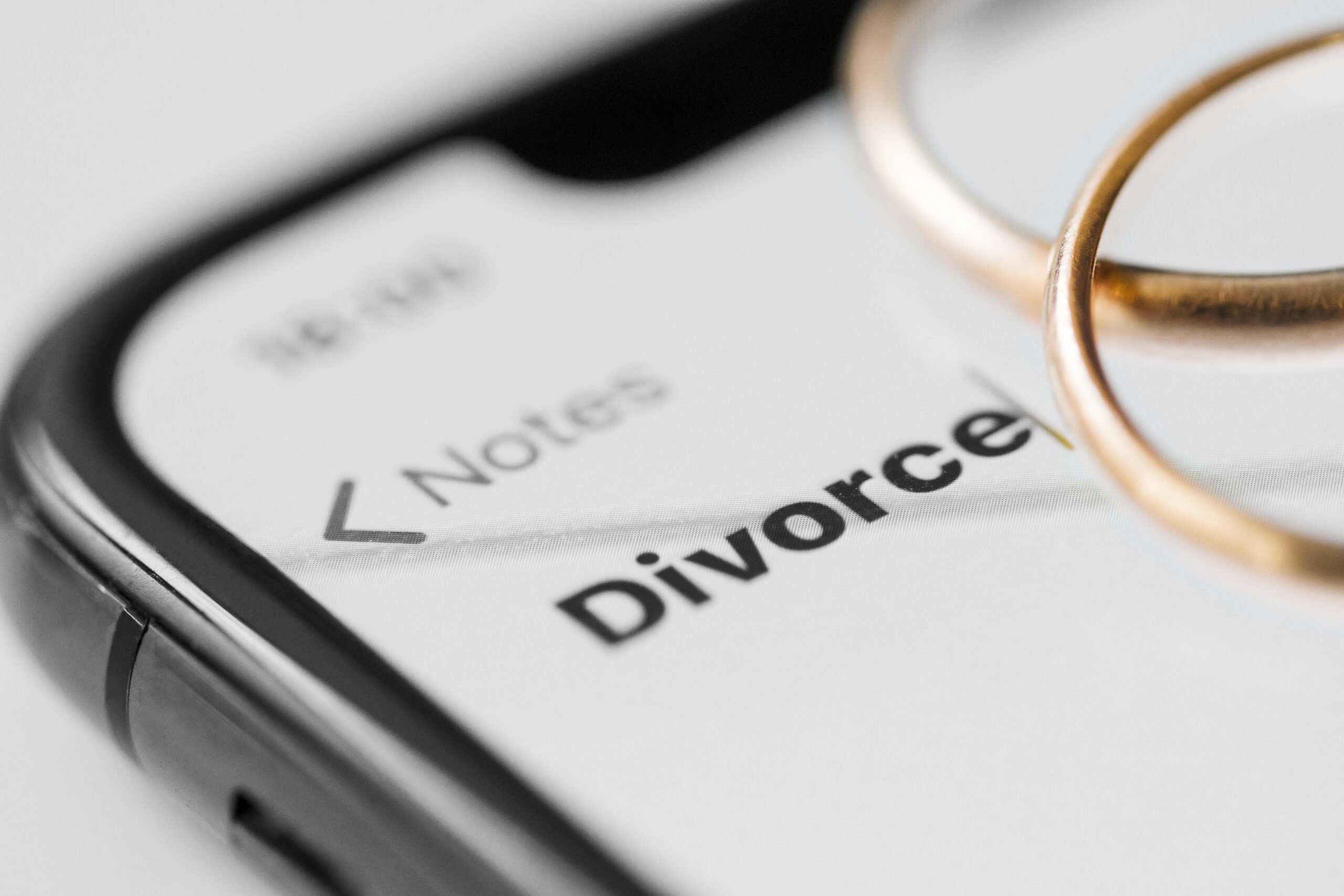 Divorce notes on phone with wedding rings